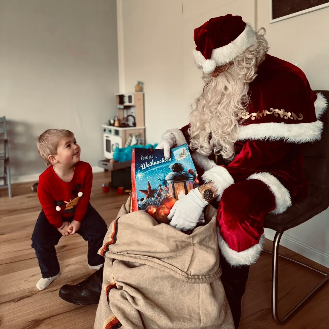Ein Junge schaut gespannt in den Geschenkesack des Weihnachtsmanns