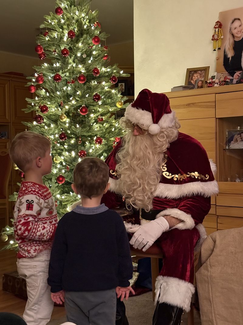 Zwei Jungen stehen vor dem Weihnachtsmann und hören ihm zu