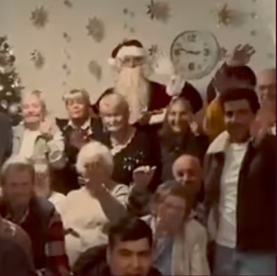 Bewohnerinnen und Bewohner einer Pflegeeinrichtung winken zusammen mit dem Weihnachtsmann